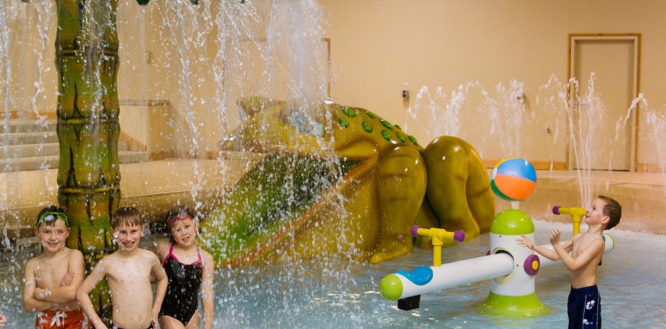 Children playing in waterpark area with seesaw and frog